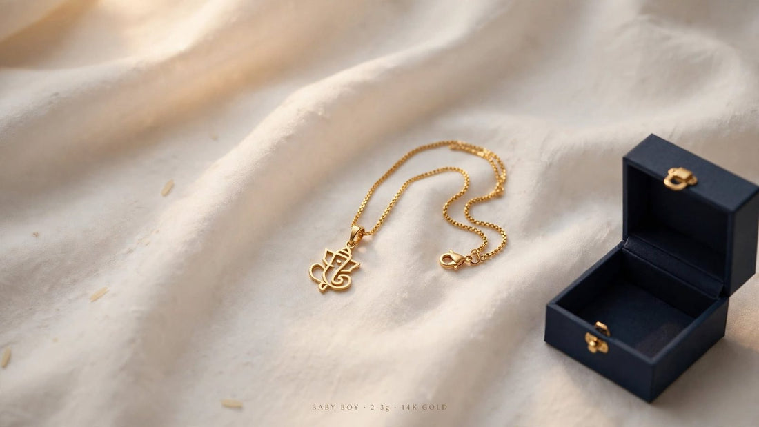 14K gold Ganesha pendant on a fine chain, laid on cream cloth beside an open navy gift box — a classic gold gift for baby boys